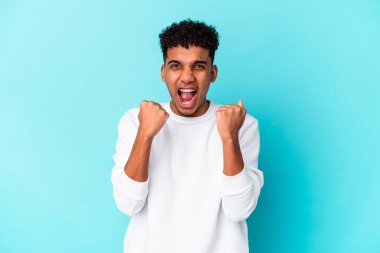 Genç Afro-Amerikan kıvırcık adamı mavi bir tezahürat yapıyor ve heyecanlanıyor. Zafer konsepti.