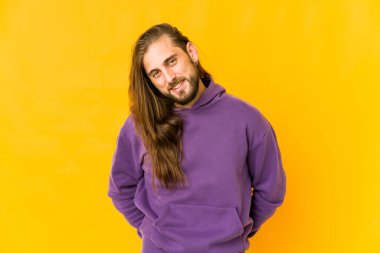 Uzun saçlı genç adam mutlu, güler yüzlü ve neşeli görün..