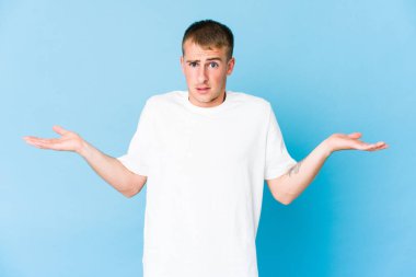 Kafası karışmış, genç, beyaz, yakışıklı bir adam. Kopyasını tutmak için omuz silkiyor..