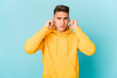 Genç beyaz yakışıklı adam kulaklarını parmaklarıyla kapatıyor, gürültülü bir ortam yüzünden stresli ve çaresiz..