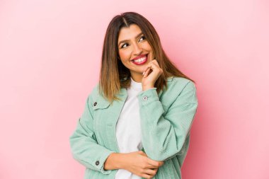 Pembe arka planda izole edilmiş genç Hintli kadın rahatlamış bir şeyin fotokopi odasına baktığını düşünüyor..