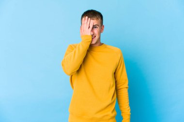 Beyaz tenli yakışıklı adam yüzünün yarısını palmiyeyle örterek eğleniyor..