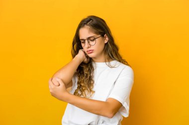 Genç beyaz kadın dirsek masajı yapıyor, kötü bir hareketin ardından acı çekiyor..