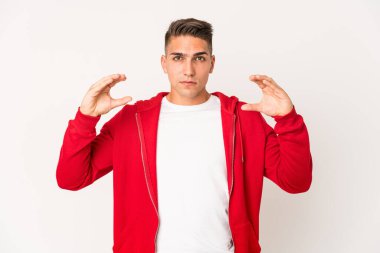 Beyaz tenli yakışıklı bir adam, elinde avuç içi bir şeyle kameraya sunuyor..