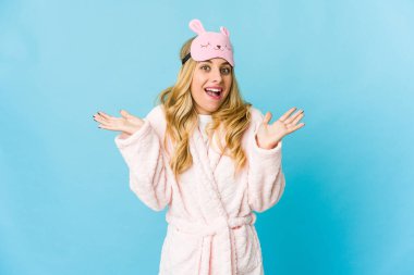 Genç sarışın, beyaz kadın pijama giyiyor. Hoş bir sürpriz yapıyor. Heyecanlı ve el kaldırıyor..