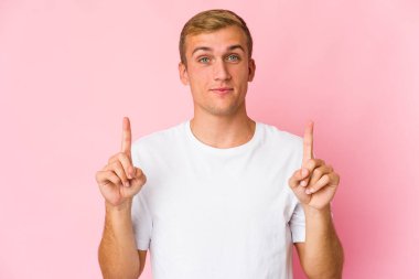 Beyaz tenli yakışıklı bir adam iki elini de havaya kaldırarak boş bir alan gösteriyor..