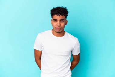 Genç afro amerikan kıvırcık adamı mavi üzgün, ciddi yüzlü, mutsuz ve hoşnutsuz.