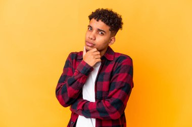 Genç Afro-Amerikalı kıvırcık adam mor üzerine izole edilmiş şüpheli, belirsiz, seni inceliyor..