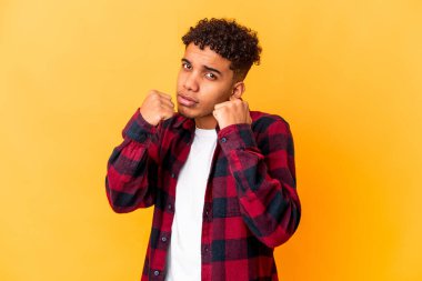 Genç Afro-Amerikalı kıvırcık adam mor üzerine izole edilmiş kameraya yumruğunu gösteriyor, agresif yüz ifadesi.