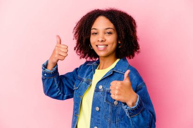 Genç Afro-Amerikan melez kadın kendini soyutlamış iki parmağını kaldırıyor, gülümsüyor ve kendinden emin..