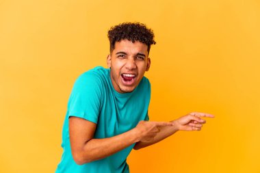 Genç Afro-Amerikan kıvırcık adamı, mor noktalar üzerinde izole edilmiş, bir fotokopi alanına işaret ediyor, heyecan ve arzusunu ifade ediyor..