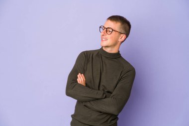 Genç beyaz yakışıklı adam kollarını kavuşturarak gülümsüyor..