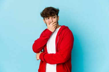 Mavi arka plandaki genç Arap korkmuş ve korkmuş..