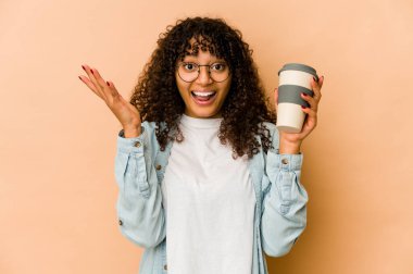 Afro-Amerikan Afro kadın elinde hazır kahveyle hoş bir sürpriz alıyor, heyecanlı ve el kaldırıyor..