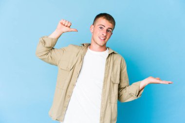 Beyaz tenli yakışıklı bir adam avucunun içinde fotokopi masası tutuyor, el üstünde tutuyor. Şaşırmış ve mutlu..