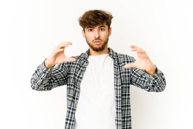 Beyaz arka planda genç bir Arap elinde avuç içi bir şeyle kameraya sunuyor..