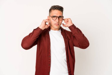 Genç beyaz yakışıklı adam kulaklarını parmaklarıyla kapatıyor, gürültülü bir ortam yüzünden stresli ve çaresiz..