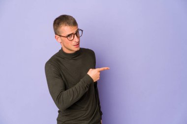 Beyaz tenli yakışıklı adam gülümsüyor ve boş alanda bir şeyler gösteriyor..