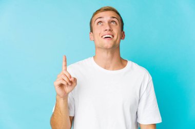 Beyaz tenli yakışıklı bir adam iki elini de havaya kaldırarak boş bir alan gösteriyor..