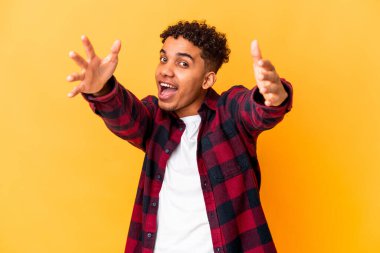 Genç Afro-Amerikalı kıvırcık adam mor üzerine izole edilmiş kameraya sarılıyor..