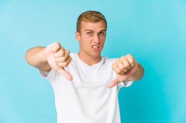 Beyaz tenli yakışıklı adam baş parmağını aşağı gösteriyor ve hoşlanmadığını söylüyor..