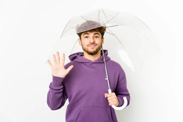 年轻的阿拉伯男子拿着一把雨伞 高兴地微笑着 用手指展示着5号 — 图库照片