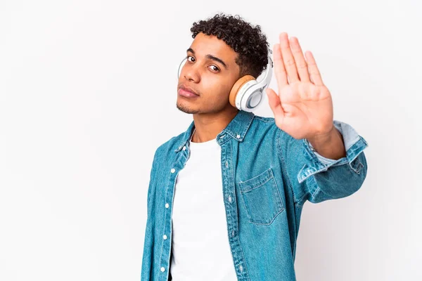 若いアフリカ系アメリカ人の巻き毛男隔離された音楽を聴くヘッドフォンで立っているアウトストップサインを示す あなたを防ぐ — ストック写真