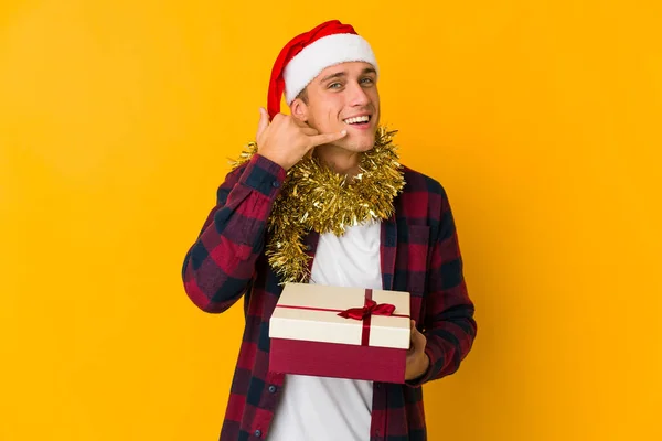 Young Caucasian Man Christmas Hat Holding Present Isolated Yellow Background — Stock Photo, Image
