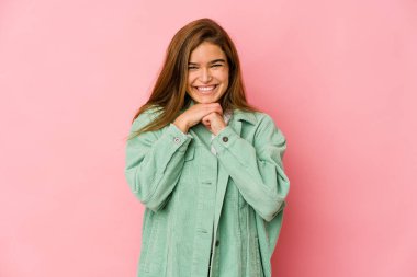 Genç, sıska, beyaz kız ellerini çenesinin altında tutuyor ve mutlu bir şekilde yan tarafa bakıyor..