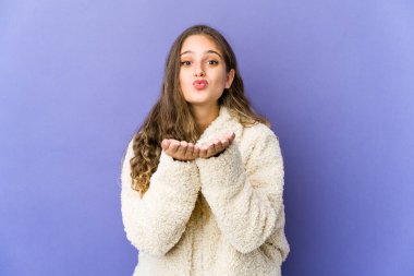 Beyaz tenli tatlı bir kadın dudaklarını katlıyor ve hava öpücüğü vermek için avuç içi tutuyor..