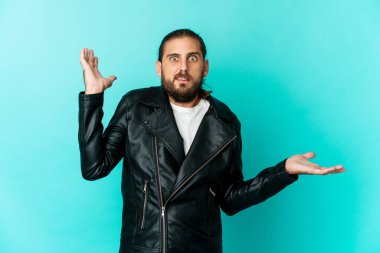 Uzun saçlı genç adam avucunda fotokopi alanı tutuyor, el üstünde tutuyor. Şaşırmış ve mutlu..