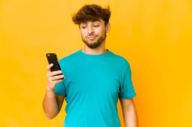 Genç Hintli adamın telefonu var, kafası karışık, kuşkulu ve kararsız..