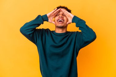 Genç Afro-Amerikan kıvırcık adamı, mor renkli kahkahalarla izole edilmiş, mutlu bir şekilde ellerini başının üstünde tutuyor. Mutluluk kavramı.