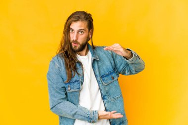 Uzun saçlı genç adam iki eliyle bir şey tutuyor, ürün sunumu..