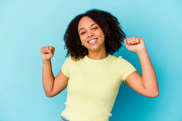 Young african american mixed race woman isolated celebrating a special day, jumps and raise arms with energy.