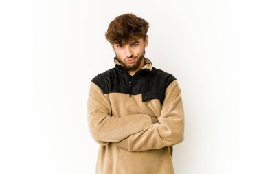 Beyaz arka planda genç bir Arap hoşnutsuzca kaşlarını çatıyor, kollarını kavuşturuyor..