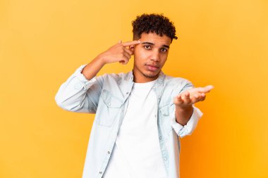 Genç Afro-Amerikalı kıvırcık adam, mor ellerde izole edilmiş ve elinde bir ürün var..