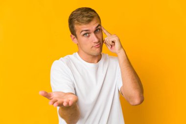 Genç, beyaz, yakışıklı bir adam elinde bir ürün tutuyor..