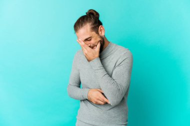 Uzun saçlı genç adam gülen mutlu, kaygısız ve doğal görünüyor..