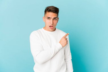 Genç, beyaz, yakışıklı bir adam tek başına, yan tarafı işaret ediyor.