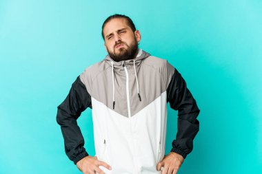 Uzun saçlı genç adam yanakları şişiriyor, yorgun bir ifade takınıyor. Yüz ifadesi kavramı.