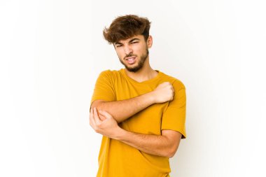 Beyaz arka planda genç bir Arap adam. Dirsek masajı yapıyor. Kötü bir hareketin ardından acı çekiyor..