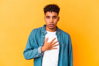 Genç Afro-Amerikalı kıvırcık adam mor renkte izole edilmiş yemin ediyor, elini göğsüne koyuyor..