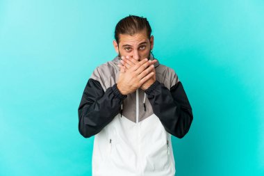 Uzun saçlı genç adam, ağzı kapalı ve elleri endişeli görünüyor..