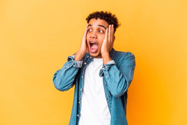 Genç Afro-Amerikalı kıvırcık adam, mor kulaklarla izole edilmiş, yüksek sesli sesler duymamaya çalışıyor..