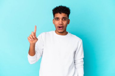 Genç Afro-Amerikan kıvırcık adamı mavi üzerine izole edilmiş. Harika bir fikri var, yaratıcılık kavramı..
