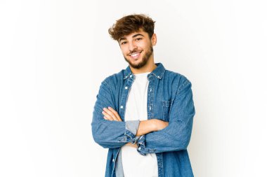 Beyaz arka plandaki genç Arap, kendinden emin, kararlılıkla kollarını kavuşturuyor..