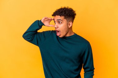 Genç Afro-Amerikalı kıvırcık adam, mor üzerine izole edilmiş, uzaklara bakıyor ve elini alnına koyuyor..