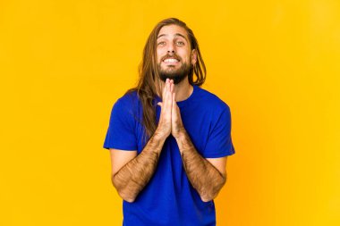 Uzun saçlı genç adam el ele tutuşup dua ediyor, kendinden emin..