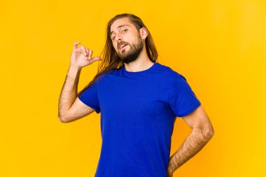 Uzun saçlı genç bir adam gömleğin fotokopi odasını elle işaret ediyor, gururlu ve kendinden emin.